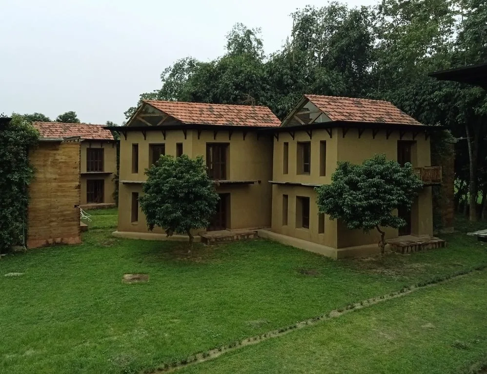 Tiled-roof mud villa among trees at Matir Maya Eco Resort